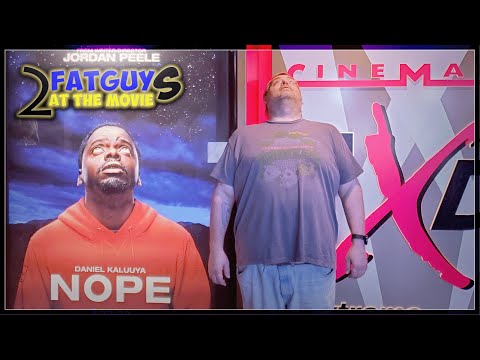 Man standing in front of cinema sign with movie poster for Fat Guy 2.